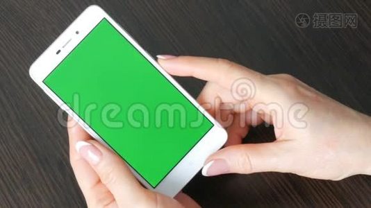 女性手与美丽的法国美甲采取白色智能手机与绿色屏幕。 使用智能手机，手持视频