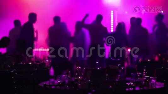 在餐馆或夜总会举行的青年聚会，在剪影的背景下摆满酒和食物的宴会桌视频