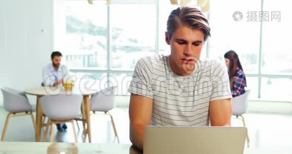 男性主管坐在办公桌上，使用笔记本电脑视频