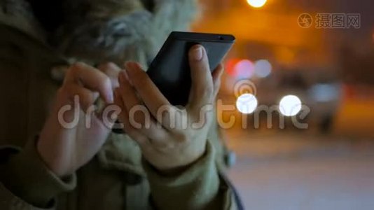 年轻女性晚上在城市里使用智能手机视频