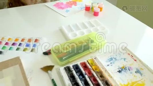 坐在桌旁，一个红发的小美女用颜料和画笔作画视频