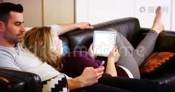 沙发上用手机和数码平板电脑的情侣视频