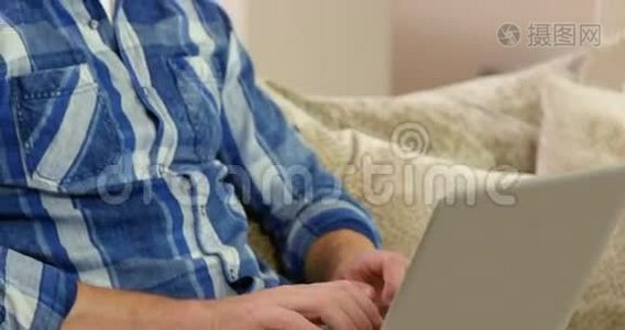 微笑的男人在沙发上用笔记本电脑视频