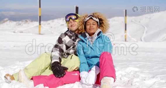 一对夫妇坐在滑雪坡上下雪视频