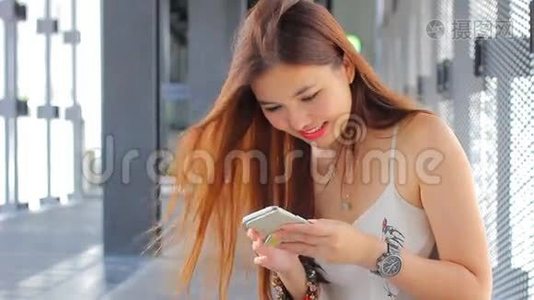 泰国成年漂亮女孩用她的智能手机和微笑。视频
