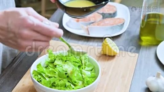 家庭厨房中的女性手的特写被添加到素叶沙拉酱中，并在木制的勺子上混合视频
