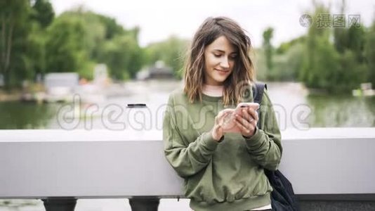 绿色的年轻女子正在河边的一座桥上发短信视频
