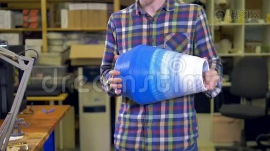 这个人拿着一个3D打印机上做的花瓶。 4K.视频