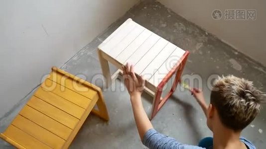 一个女孩在画椅子。 用你自己的手在公寓里修理。视频