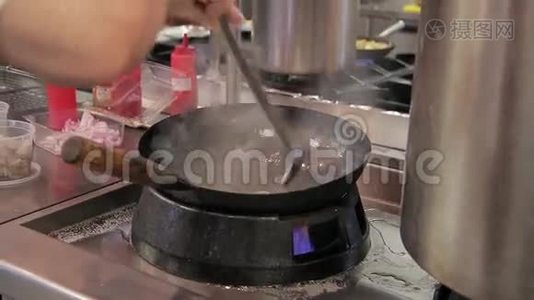 厨师在炉子上准备食物，在现代化的大型餐厅厨房里用火煎锅。视频