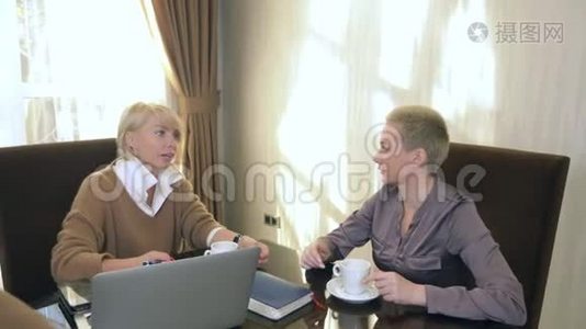 两个女人坐在笔记本电脑前的办公室里说话视频