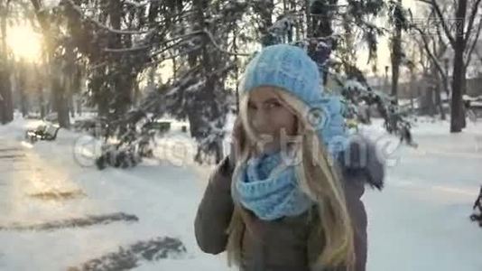 穿着温暖的帽子和围巾在冬季公园散步的年轻漂亮女士视频