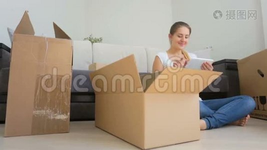年轻女子在收拾东西搬到新公寓时使用数码平板电脑的多利镜头视频