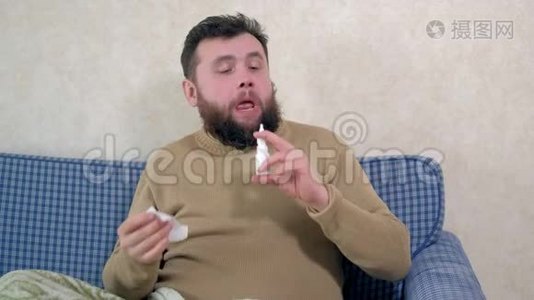 一个感冒的人坐在沙发上。 他在鼻子里喷了一种特殊的鼻腔喷雾剂。视频