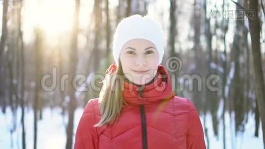美丽的年轻女子站在冬天的公园里，微笑着，玩得很开心。 慢动作录像。视频