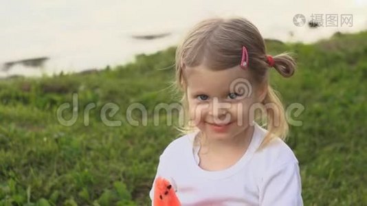 小可爱的小女孩吃红西瓜坐在池塘边的绿草上视频