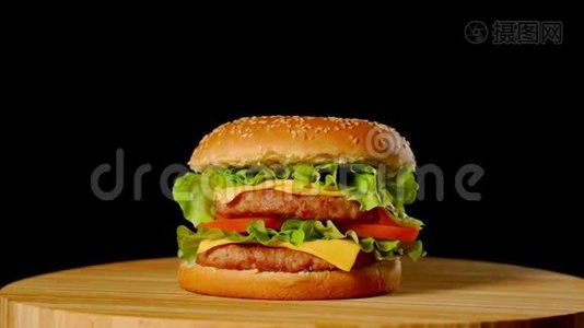 大汉堡配牛肉、西红柿、蘑菇和黄瓜，配上融化的奶酪，在黑色的木板上旋转视频