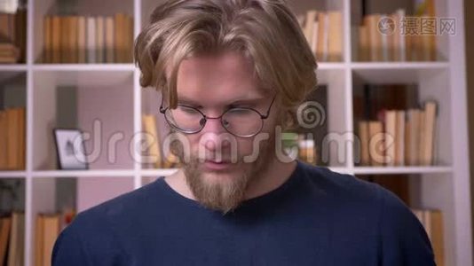室内大学图书馆里戴眼镜看镜头的成年男生特写镜头视频