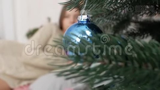 那个女孩躺在圣诞树背景上的床上。 新年视频