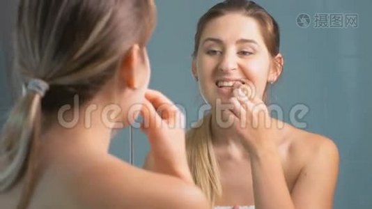 4K镜头显示年轻女子在浴室的镜子前检查牙齿视频