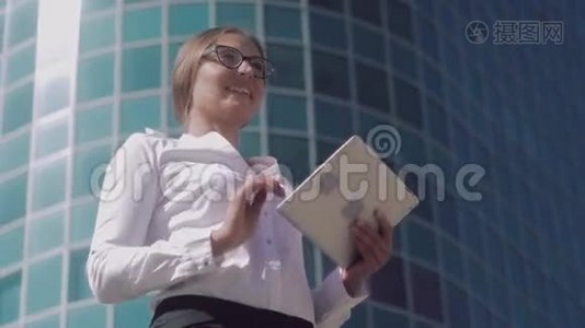 戴眼镜的微笑商务女性正在制作她的平板电脑视频