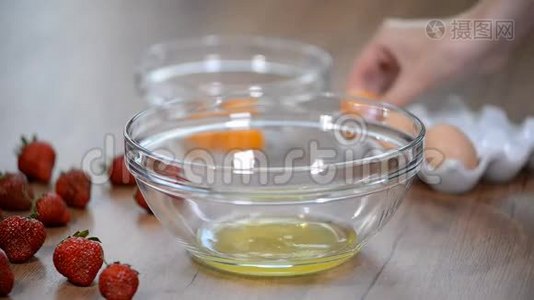 女人的手打破一个鸡蛋，以分离蛋清和蛋黄和鸡蛋壳的背景。视频