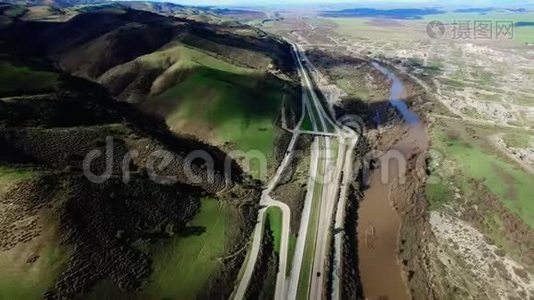 一条河附近的公路和美丽的绿色田野和山丘的史诗般的镜头视频