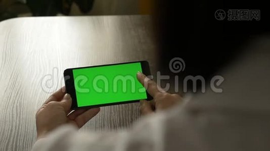女人拿着一部绿色屏幕的手机。 供你的视频内容..视频