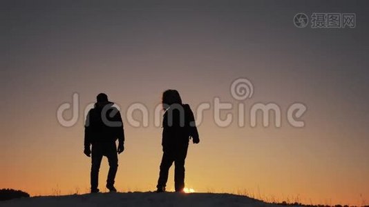 两个徒步旅行的游客走在日落山顶剪影 团队合作旅游业务理念。 两个人视频