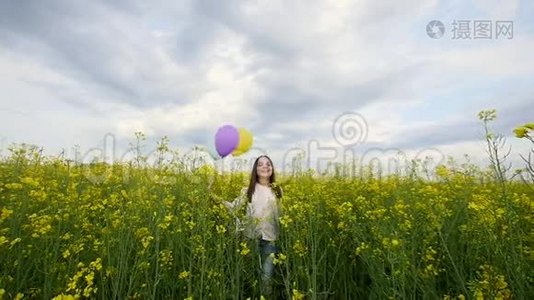 快乐的女孩带着气球在麦田里散步视频