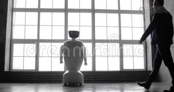 一个时尚的男人与机器人交流，把一只塑料机械手臂按在机器人身上，握手。 控制系统视频