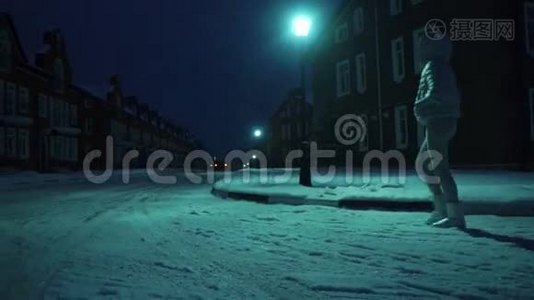 一个穿着银色冬衣的孤独女孩，晚上在居民区的雪地上散步视频