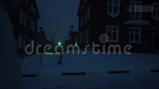 一个孤独的年轻女子，穿着银色夹克，晚上在住宅区的雪地上散步视频