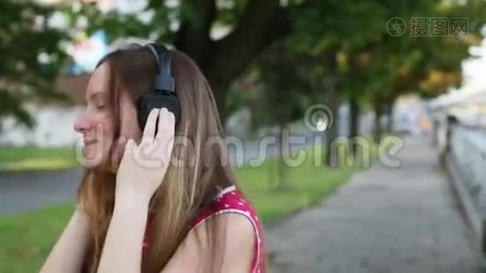 一个年轻女孩在户外耳机里欣赏音乐的特写镜头。视频