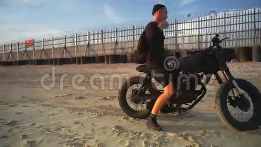 日落时分，摩托车手在海滩上驾驶摩托车。 慢动作。视频