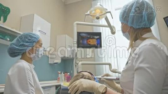 医生用特殊的口腔检查数字微相机检查牙齿。 监控牙医和病人看录像视频