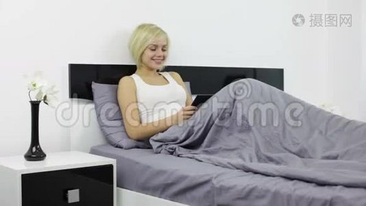 女人躺在床上用黑色数码平板电脑视频