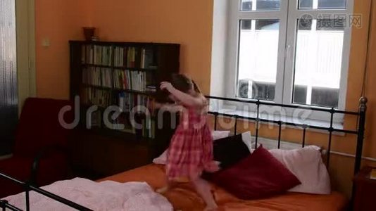 一个可爱的小女孩在床上跳。 父母的卧室和她的女儿正在床上跳跃视频