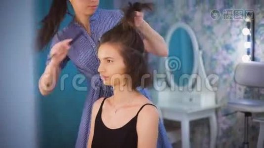 理发师梳着一个美丽的年轻黑发女郎的头发。视频