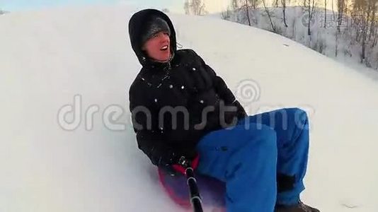 快乐的人骑着雪管在雪道上微笑。慢动作。 冬天的雪景。 户外运动视频