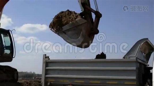 一辆挖掘机斗正在用灰色车身装满一辆卡车。视频