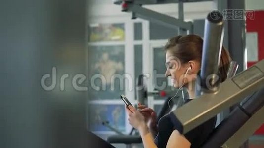 健身房里一个女孩带着手机和耳机的特写镜头视频