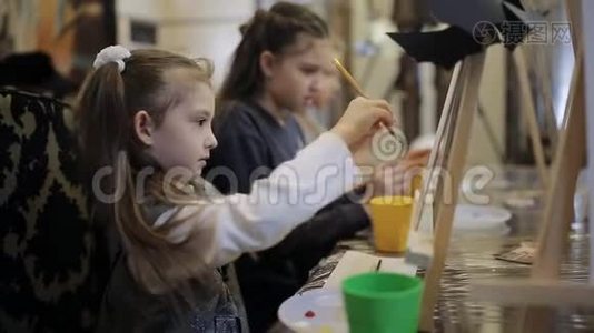 艺术学校，一群带画架的孩子用画笔和颜料作画视频
