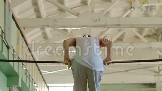 体操运动员在健身房的水平杆上旋转视频