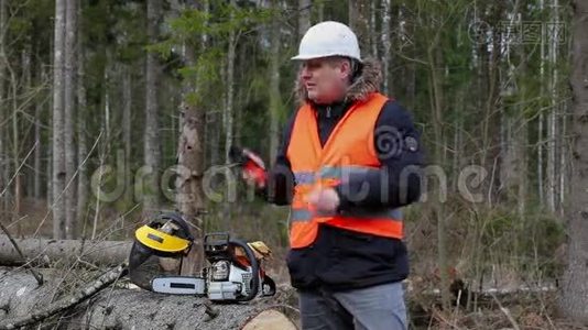 伐木工人在森林里的电锯旁打电话视频