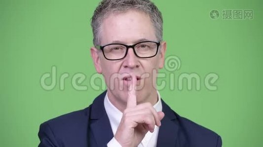 一张成熟商人用手指在嘴唇上拍摄的摄影棚视频
