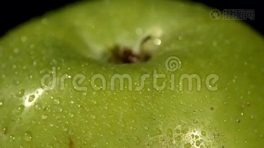 在黑色上分离的湿绿苹果顶部，旋转视频