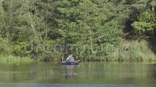 两个穿着橡皮船的渔夫在河上划桨。 人在阳光明媚的森林里湖上钓鱼。 斯特拉克河-视频