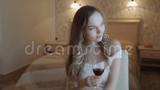 年轻的商务女性在她的酒店卧室放松，从窗口的一杯红酒喝。 豪华客房视频
