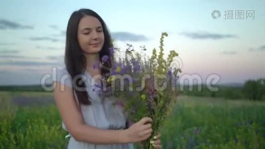 年轻的女人带着一束田野的花走着。视频